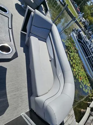 Slide: The Image of 2023 Bennington 24 SSR boat with sleek gray seating, docked near lily pads. - 9