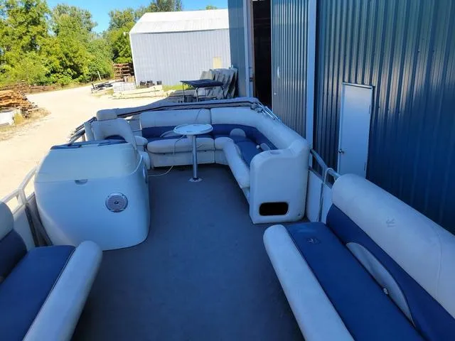 Slide: The Image of 2008 JC MFG Neptune 23 pontoon boat with spacious seating and table, docked near metal building. - 7