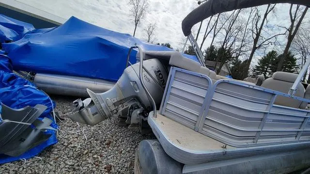 Slide: The Image of 2000 Godfrey Pontoons San Pan boat with Honda outboard motor, parked on gravel. - 11