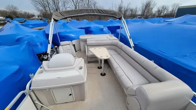 Slide: The Image of 2000 Godfrey Pontoons San Pan with beige seating, surrounded by blue-covered boats. - 3