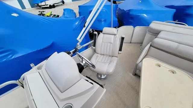 Slide: The Image of 2000 Godfrey Pontoons San Pan interior with helm, seating, and covered boats in background. - 4