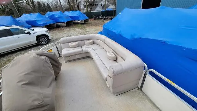 Slide: The Image of 2000 Godfrey Pontoons San Pan with beige seating, parked near blue-covered boats. - 6