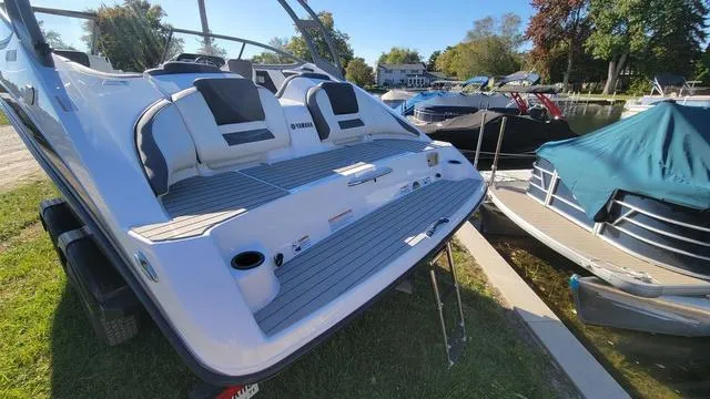 Slide: The Image of 2022 Yamaha AR210 boat with sleek design, docked near other boats on a sunny day. - 17