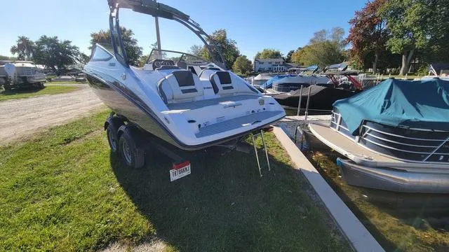 Slide: The Image of 2022 Yamaha AR210 boat on trailer, parked near a marina with other boats. - 18