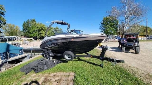 Slide: The Image of 2022 Yamaha AR210 boat on trailer, parked on grass under clear blue sky. - 8