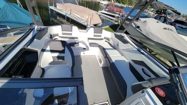 Slide: The Image of 2022 Yamaha Boats AR210 interior with spacious seating, docked near other boats. - 9