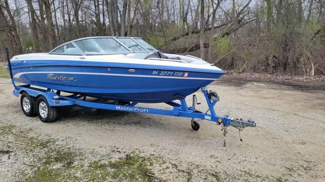 Slide: The Image of 2004 MasterCraft MariStar 210 boat on trailer in wooded area. - 1