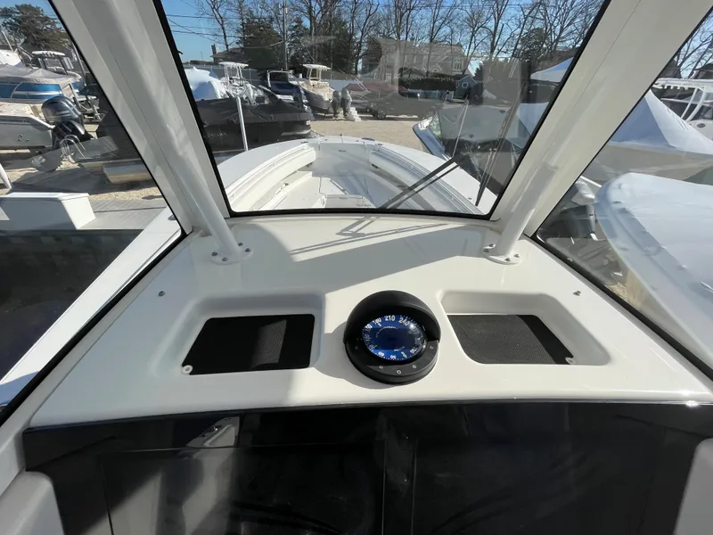 Slide: The Image of 2022 Regulator 28 boat cockpit with compass, surrounded by other boats in a marina. - 13