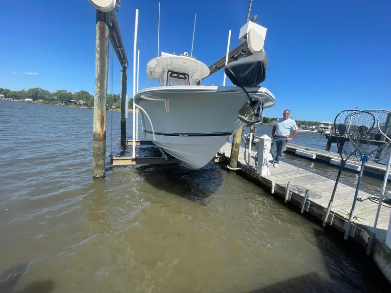 Slide: The Image of 2022 Regulator 28 boat on lift at dock, clear blue sky, calm water. - 27