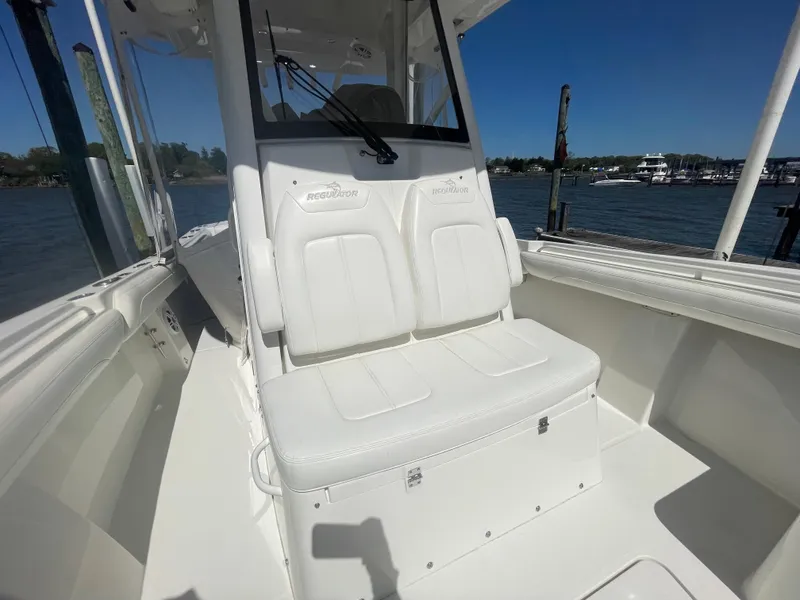 Slide: The Image of 2022 Regulator 28 boat interior with white seating and console, docked by the water. - 33