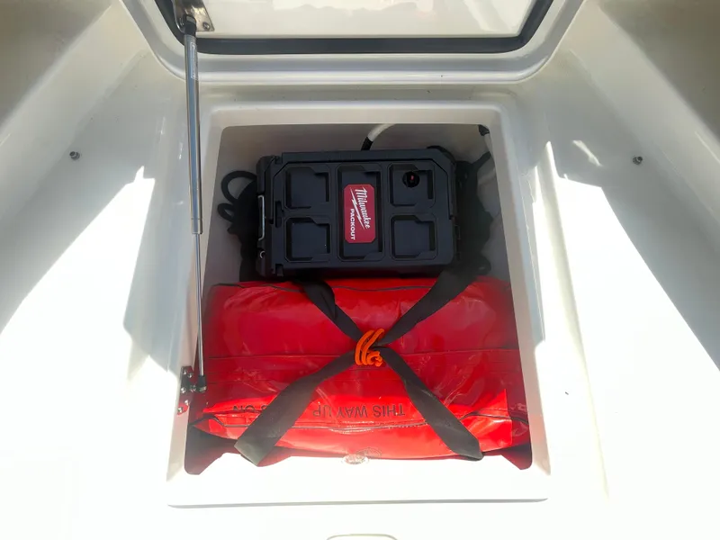 Slide: The Image of Storage compartment in a 2022 Regulator 28 boat with safety equipment and toolbox. - 35