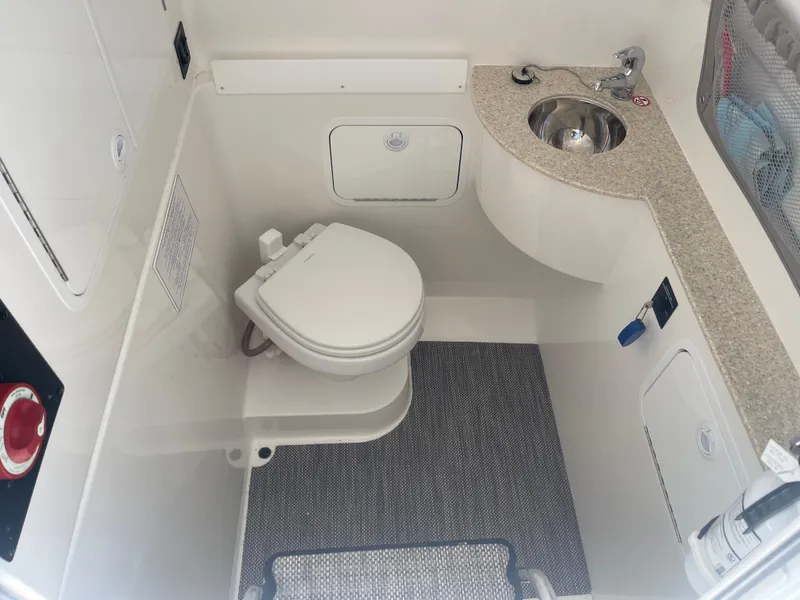 Slide: The Image of 2022 Regulator 28 boat bathroom with toilet, sink, and storage compartments. - 39