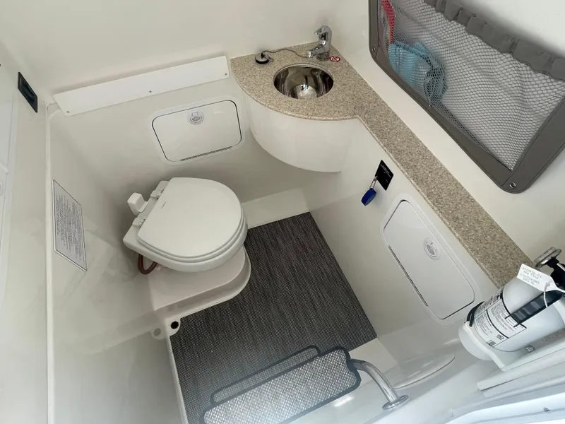 Slide: The Image of 2022 Regulator 28 boat bathroom with toilet, sink, and storage compartments. - 42