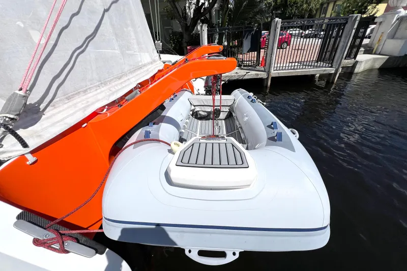 Slide: The Image of Inflatable boat attached to a Balance 482 sailboat, docked by the water. - 155