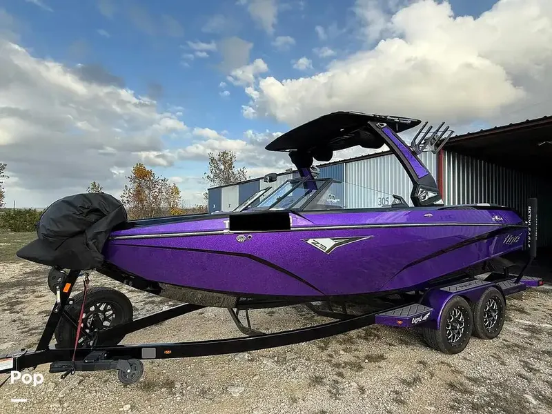Slide: The Image of 2022 Tigé Z3 boat in vibrant purple on a trailer, parked outdoors. - 2