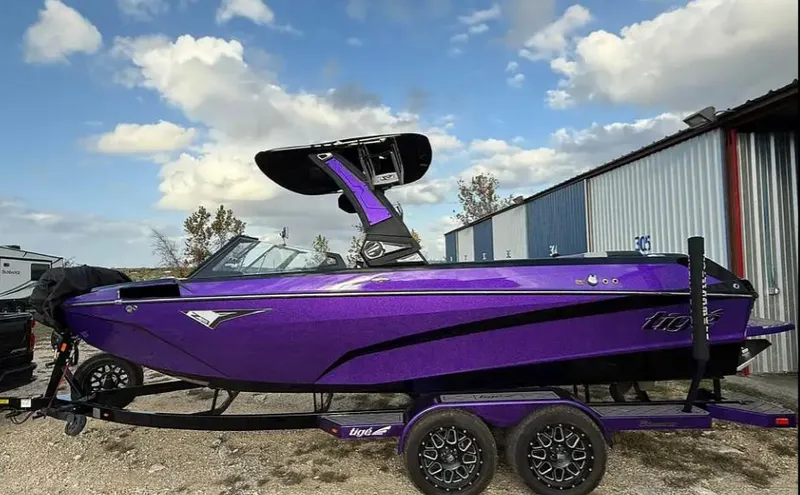 Slide: The Image of 2022 Tigé Z3 boat in vibrant purple, parked on a trailer under a partly cloudy sky. - 3