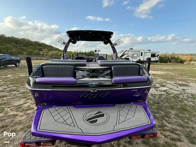 Slide: The Image of 2022 Tigé Z3 boat with purple accents, parked on grass under a cloudy sky. - 4
