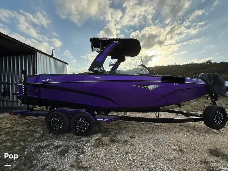 Slide: The Image of 2022 Tigé Z3 boat in vibrant purple, parked outdoors near a metal building. - 7