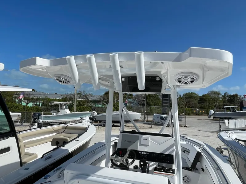 Slide: The Image of 2025 Blackfin 222CC boat with T-top and rod holders, docked under clear blue sky. - 12