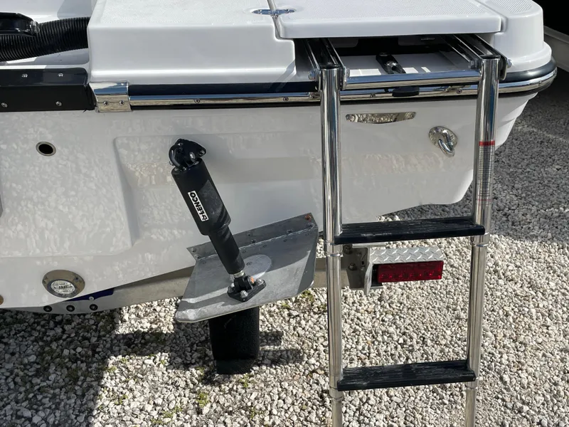 Slide: The Image of 2025 Blackfin 222CC boat with ladder and trim tab on gravel surface. - 22