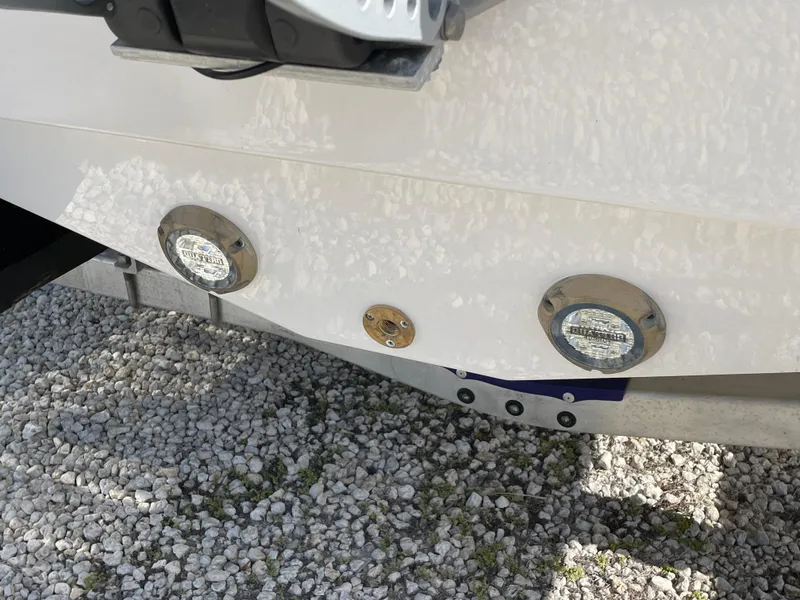 Slide: The Image of 2025 Blackfin 222CC boat hull with underwater lights on gravel surface. - 24