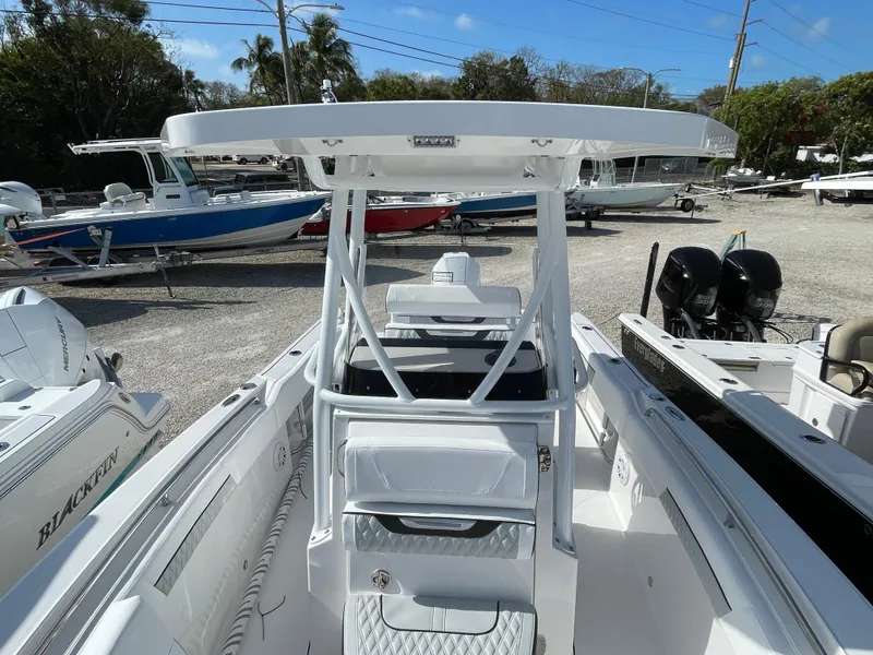 Slide: The Image of 2025 Blackfin 222CC boat with T-top, parked in a marina with other boats. - 8