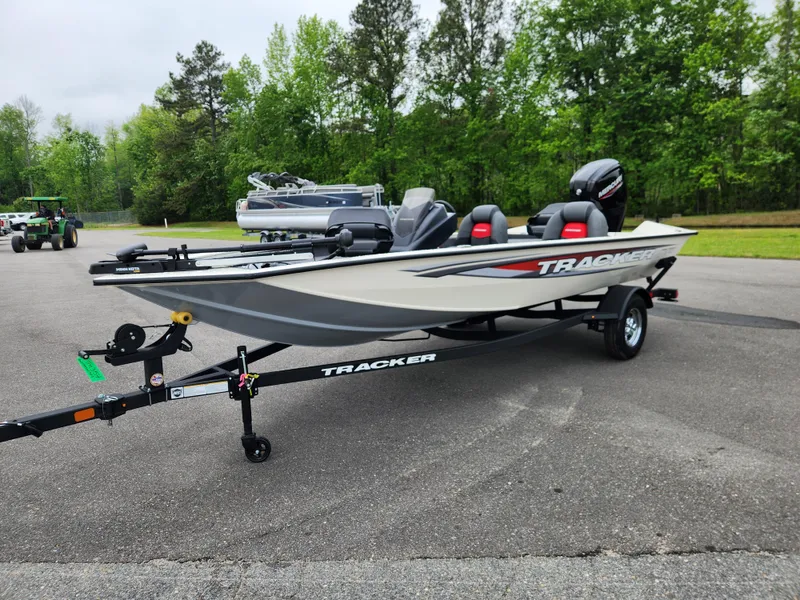 Slide: The Image of 2025 Tracker Pro Team 175 boat on trailer, parked outdoors with trees in background. - 6