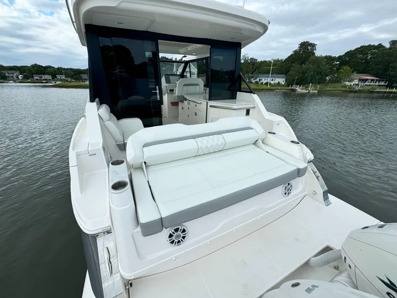 Slide: The Image of 2026 Regal 36 XO yacht with spacious deck and seating, docked on a serene waterway. - 11