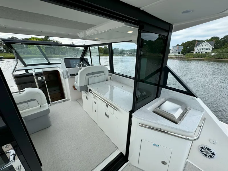 Slide: The Image of Interior of 2026 Regal 36 XO yacht with modern helm and seating, overlooking serene waters. - 15
