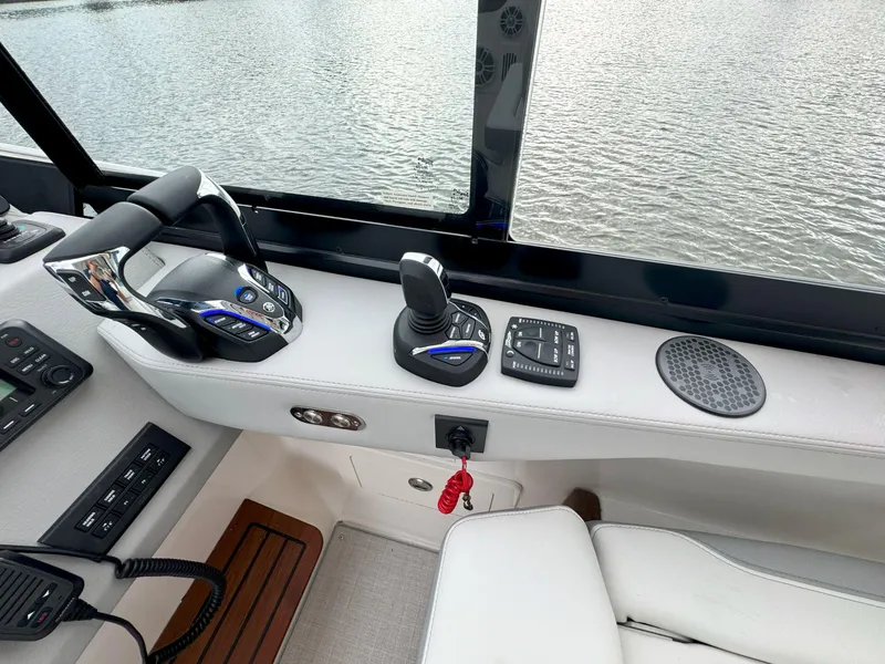 Slide: The Image of 2026 Regal 36 XO boat controls with throttle, joystick, and speaker by the water. - 27