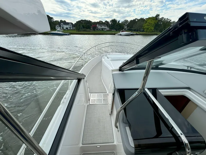 Slide: The Image of 2026 Regal 36 XO boat deck view on a calm river with houses in the background. - 35