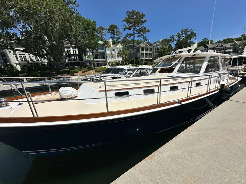 Slide: The Image of 2004 Grand Banks 49 Eastbay HX yacht docked in a marina, surrounded by trees and buildings. - 10