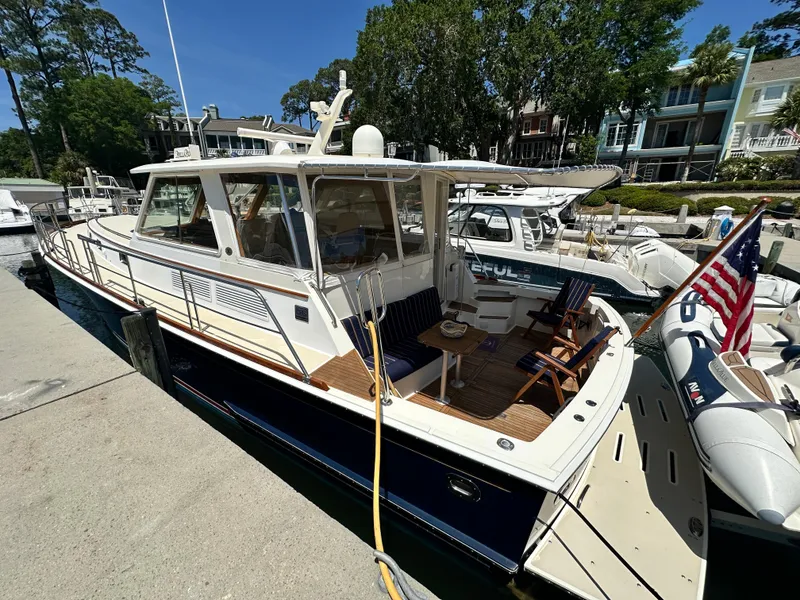 Slide: The Image of 2004 Grand Banks 49 Eastbay HX yacht docked, featuring a spacious deck and American flag. - 13