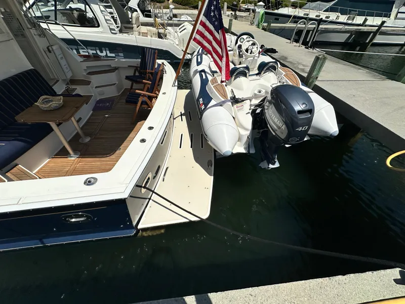 Slide: The Image of 2004 Grand Banks 49 Eastbay HX yacht docked with inflatable boat and American flag. - 16