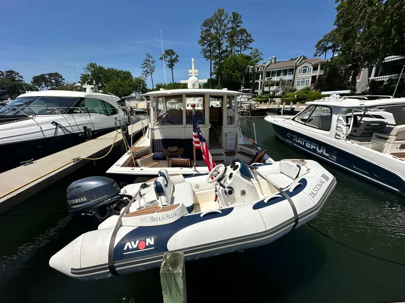 Slide: The Image of 2004 Grand Banks 49 Eastbay HX docked with inflatable boat, surrounded by other yachts. - 2