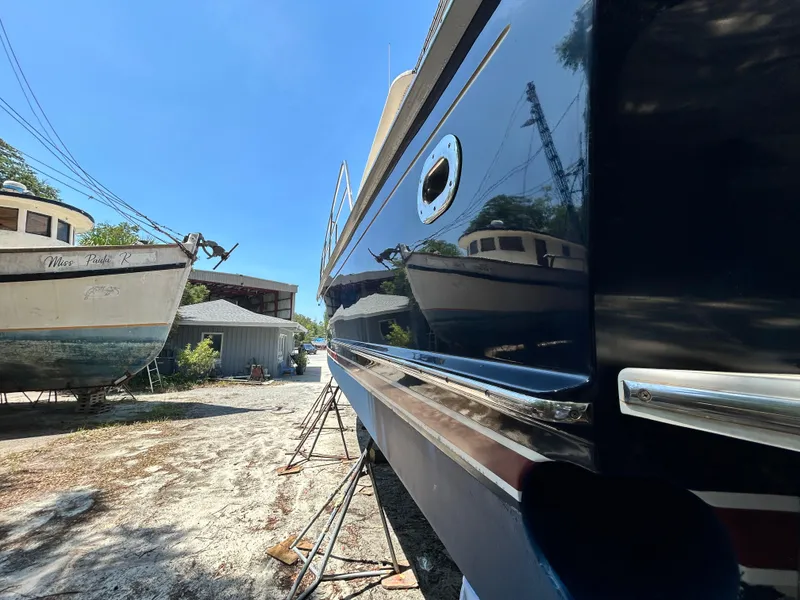 Slide: The Image of 2004 Grand Banks 49 Eastbay HX yacht in a boatyard, reflecting nearby vessels. - 21