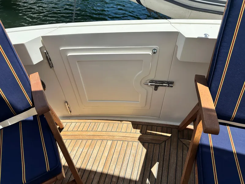 Slide: The Image of 2004 Grand Banks 49 Eastbay HX yacht deck with blue-striped chairs and wooden flooring. - 28