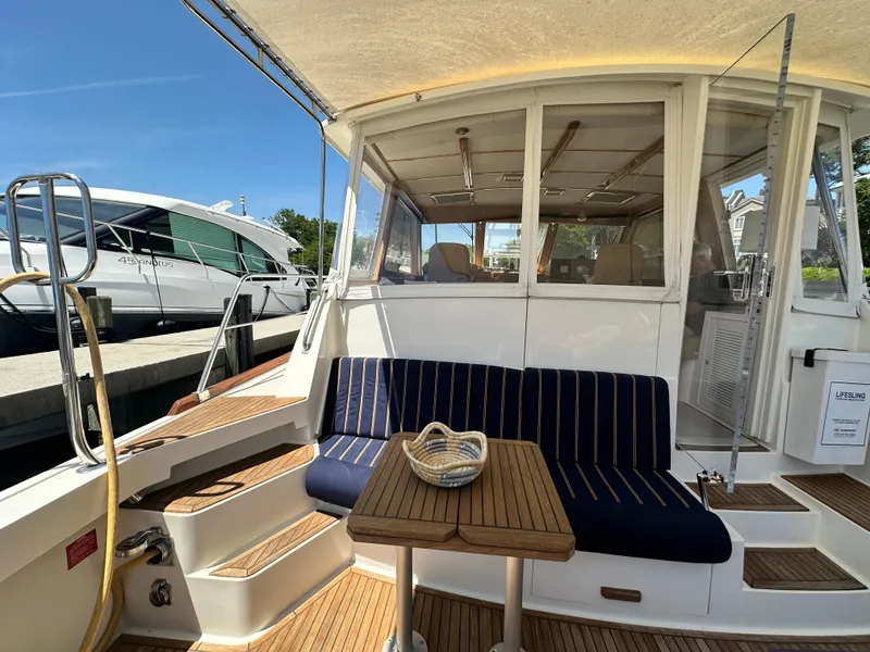 Slide: The Image of 2004 Grand Banks 49 Eastbay HX yacht with striped seating and wooden table on deck. - 34