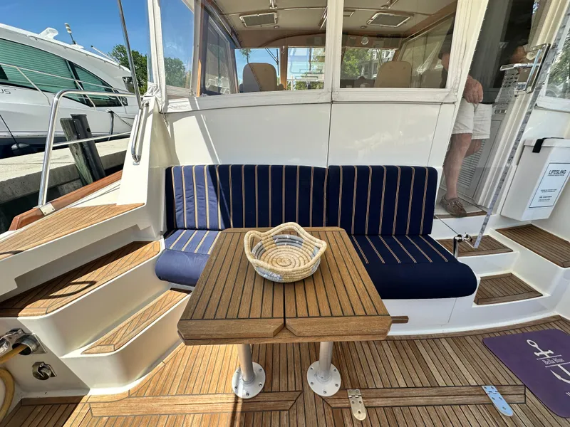 Slide: The Image of 2004 Grand Banks 49 Eastbay HX yacht with teak deck, cushioned seating, and wooden table. - 36