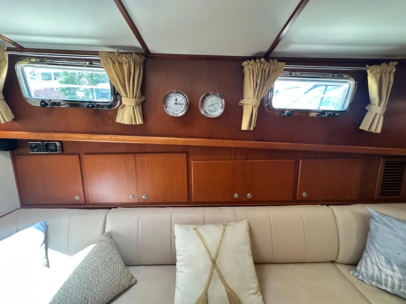 Slide: The Image of Interior of 2004 Grand Banks 49 Eastbay HX with wood paneling, windows, and beige seating. - 48