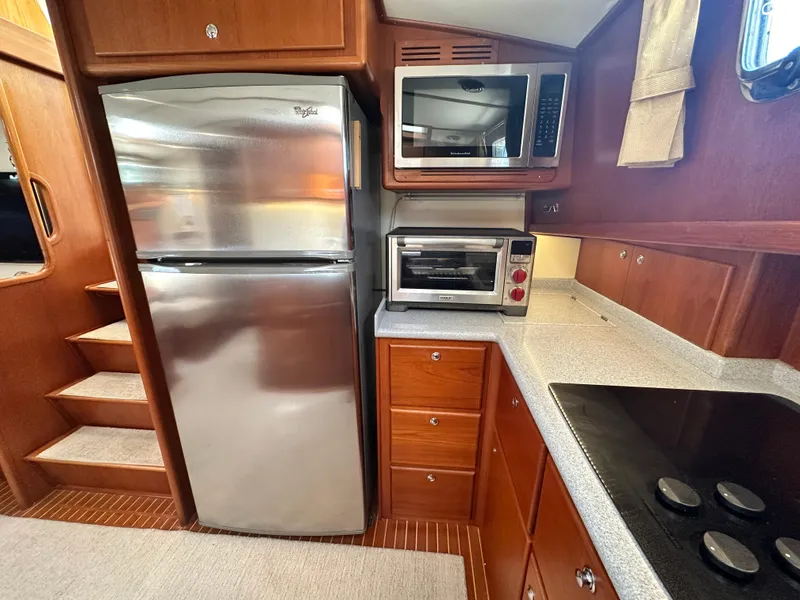 Slide: The Image of 2004 Grand Banks 49 Eastbay HX yacht kitchen with stainless steel appliances and wooden cabinetry. - 53