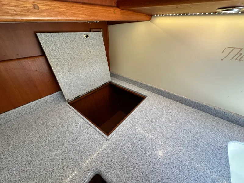 Slide: The Image of 2004 Grand Banks 49 Eastbay HX interior with open storage compartment on speckled countertop. - 63