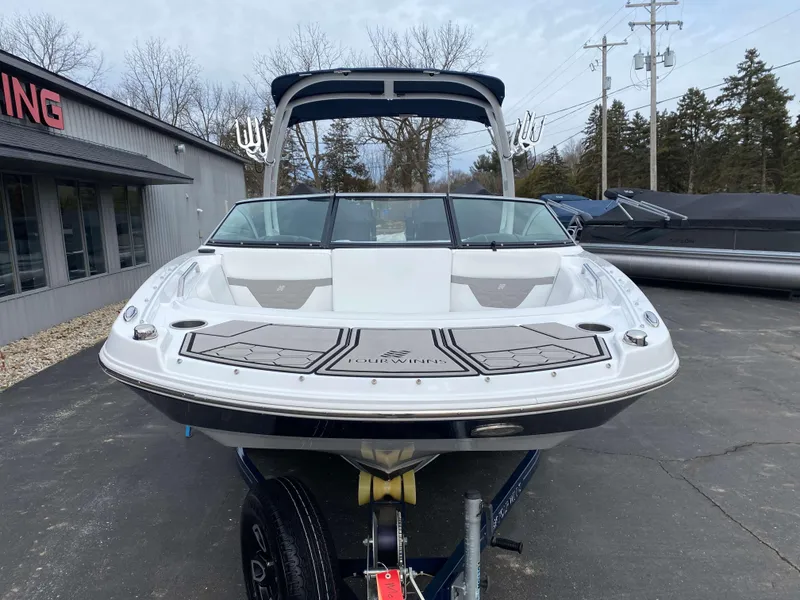 Slide: The Image of 2022 Four Winns HD2 Surf boat on trailer, front view, parked outdoors. - 19