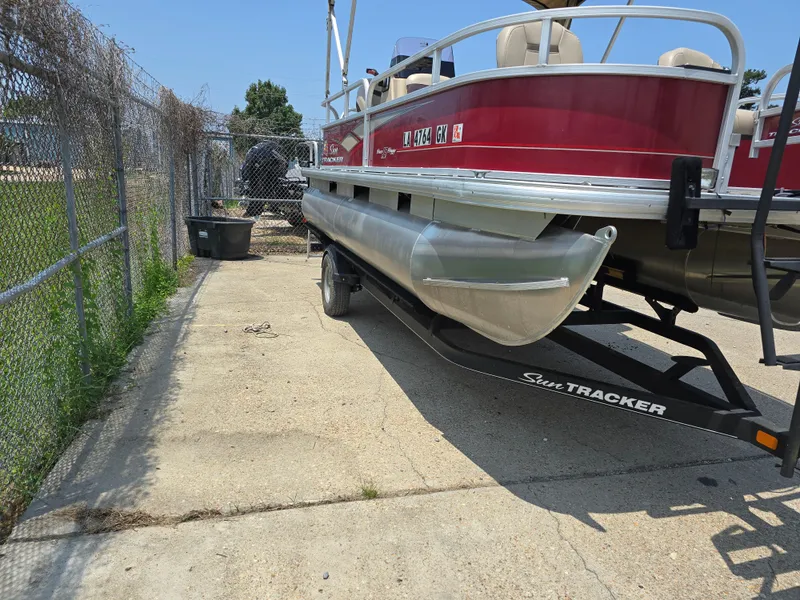 Slide: The Image of 2019 Sun Tracker Bass Buggy 18 DLX pontoon boat on trailer, parked outdoors. - 4