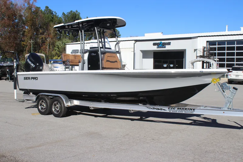 Slide: The Image of 2025 Sea Pro 250 Bay boat on trailer, parked outside a marine dealership. - 0