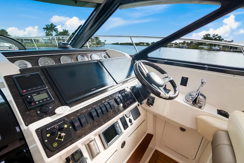 Slide: The Image of Helm of 2013 Sea Ray 410 Sundancer yacht with modern controls and scenic water view. - 12
