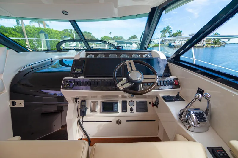 Slide: The Image of 2013 Sea Ray 410 Sundancer helm with steering wheel, controls, and navigation instruments. - 14