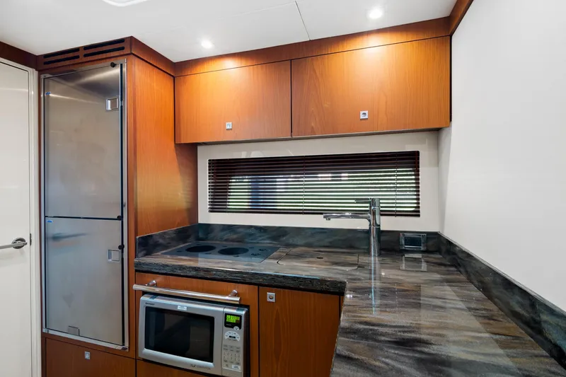 Slide: The Image of Modern kitchen interior of 2013 Sea Ray 410 Sundancer yacht with wood cabinets and stainless appliances. - 19