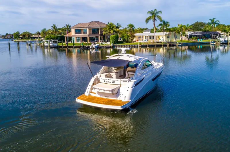 Slide: The Image of 2013 Sea Ray 410 Sundancer yacht cruising in a scenic waterfront area. - 4