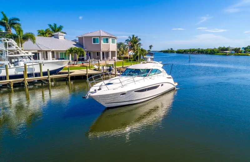 Slide: The Image of 2013 Sea Ray 410 Sundancer yacht cruising near waterfront homes on a sunny day. - 5